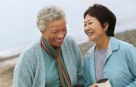 Two cheerful middle aged female friends talking on the beach