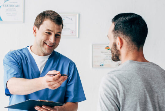 panoramic shot of smiling Physiotherapist with diagnosis near patient in hospital