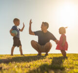 Father playing with his children having fun at the park. Parenting and raising children concept.