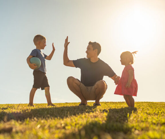 Father playing with his children having fun at the park. Parenting and raising children concept.