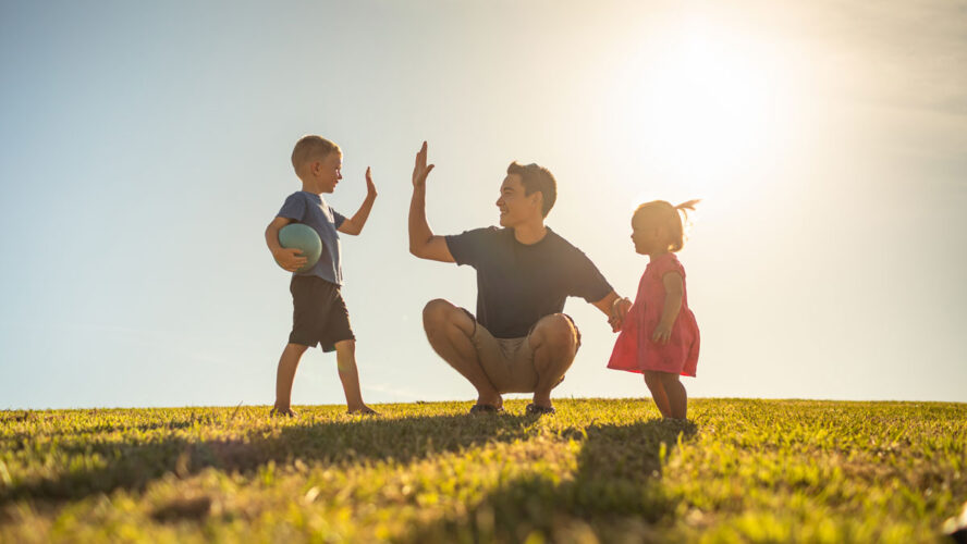 Father playing with his children having fun at the park. Parenting and raising children concept.
