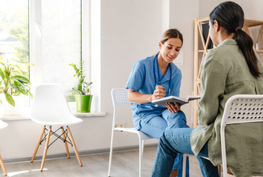 White woman doctor talking with patient while working in her office