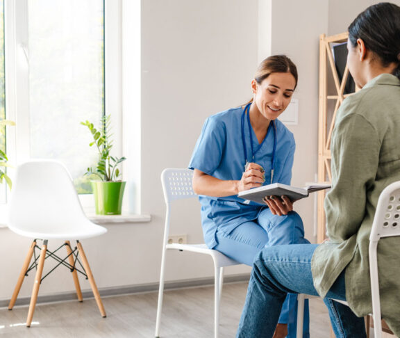 White woman doctor talking with patient while working in her office