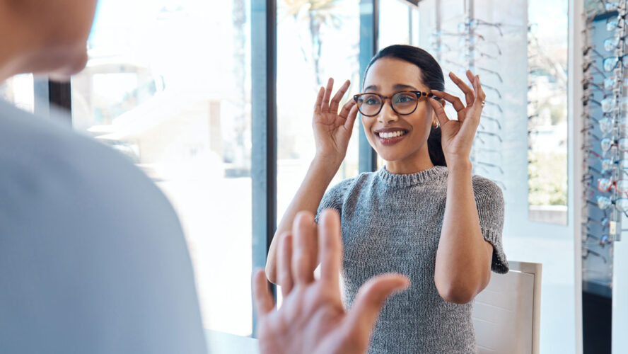 A customer buying, testing or trying on glasses at an optometrist store or shop. Health care eye wear professional picking or selling a pair of new eyeglasses to a young female client or patient