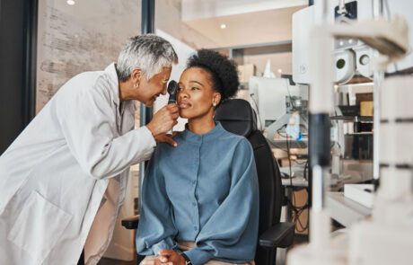 Doctor, vision or black woman in eye exam consultation or assessment for eyesight at optometrist office. Mature or senior optician helping a customer testing or checking iris or retina visual health