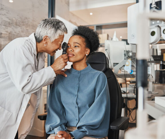 Doctor, vision or black woman in eye exam consultation or assessment for eyesight at optometrist office. Mature or senior optician helping a customer testing or checking iris or retina visual health
