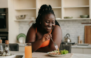 Beautiful curvy African woman enjoying healthy eating for lunch at home