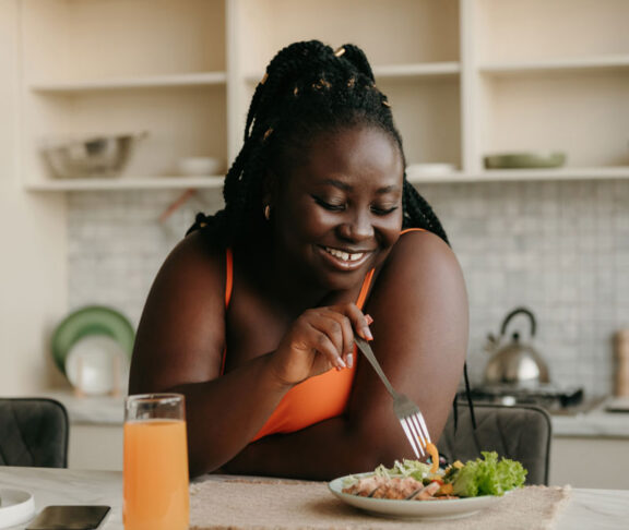 Beautiful curvy African woman enjoying healthy eating for lunch at home