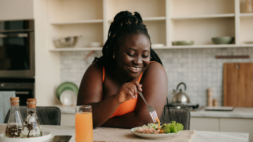 Beautiful curvy African woman enjoying healthy eating for lunch at home