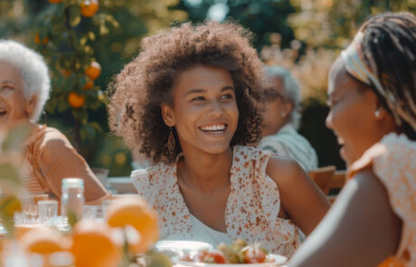 Laughing Multiethnic Female Talking with a Senior Woman at a Summer Garden Party. Children, Adults, and Older People Gathered at a Table to Enjoy Food and Have Fun