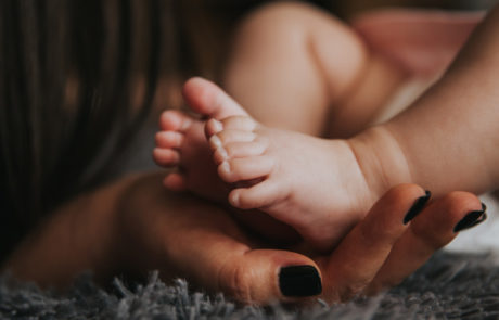 Adult hand cups baby's feet