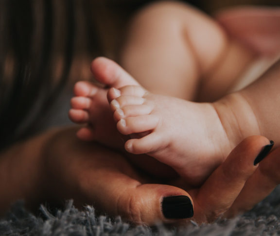 Adult hand cups baby's feet