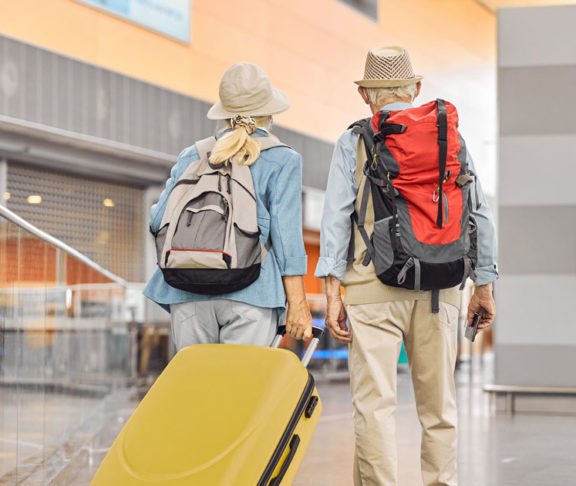 Two Caucasian elderly travelers standing at the airport