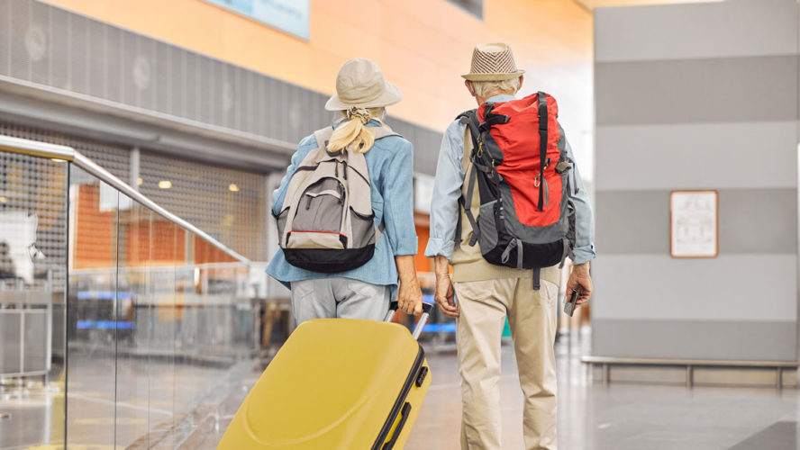 Two Caucasian elderly travelers standing at the airport