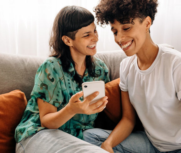 Two lesbian lovers using a smartphone together at home