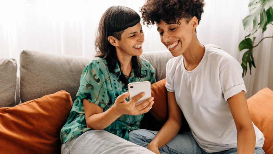 Two lesbian lovers using a smartphone together at home