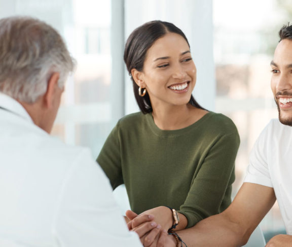 Shot of a young couple sitting with their obstetrician and holding hands during a consultation in the clinic