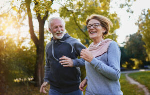 Cheerful active senior couple jogging in the park