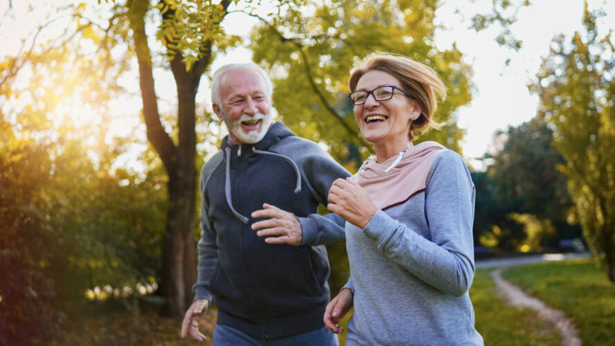 Cheerful active senior couple jogging in the park