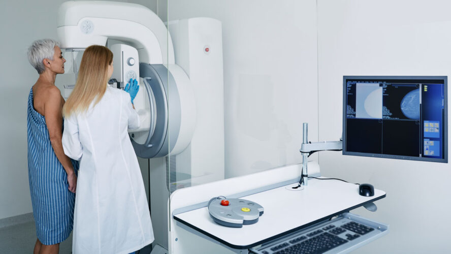 Mammogram procedure in medical clinic, mammography. Female mammologist positions mature woman at imaging machine to receive mammogram