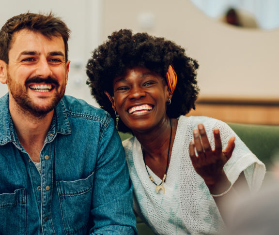 Young multiracial couple smiling because solved conflict at couple therapy session with a counseling adviser and. Diverse spouses being happy with a psychologist advises. Copy space.