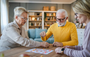 Group of people senior man and women play leisure board game at home