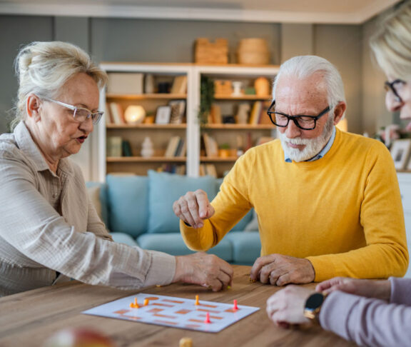 Group of people senior man and women play leisure board game at home