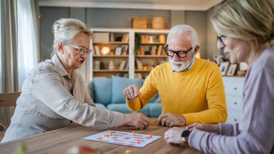 Group of people senior man and women play leisure board game at home
