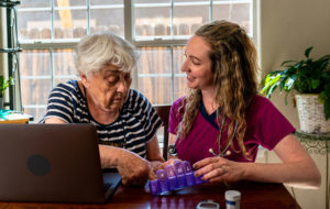 A young nurse is explaining an elderly woman's daily medications to her.