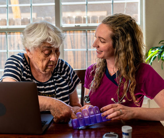 A young nurse is explaining an elderly woman's daily medications to her.