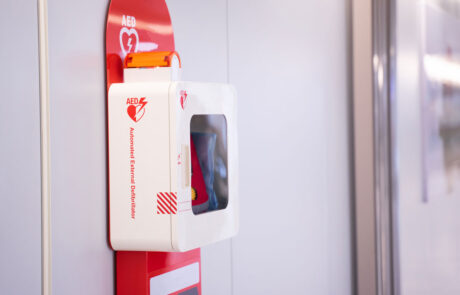 Automatic external defibrillator mounted on white wall.