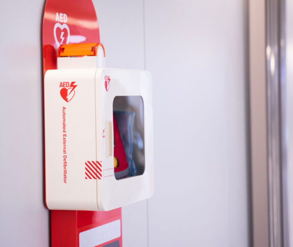 Automatic external defibrillator mounted on white wall.