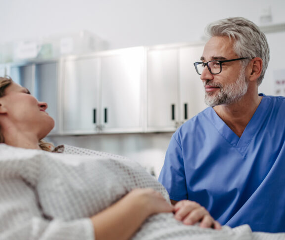 Doctor talking with worried female patient, emotional support before surgery. Friendly male doctor reassuring the patient.