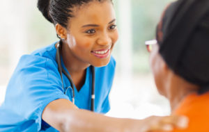 African medical nurse comforting senior patient