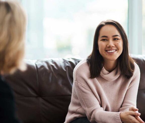 Therapy, happy women have a conversation on sofa and speaking or talking with a psychologist. Mental health or communication, support or consulting and people on couch have a discussion together
