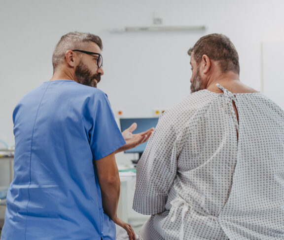 Supportive doctor soothing a worried overweight patient, discussing test result in emergency room. Illnesses and diseases in middle-aged men's health. Compassionate physician supporting stressed