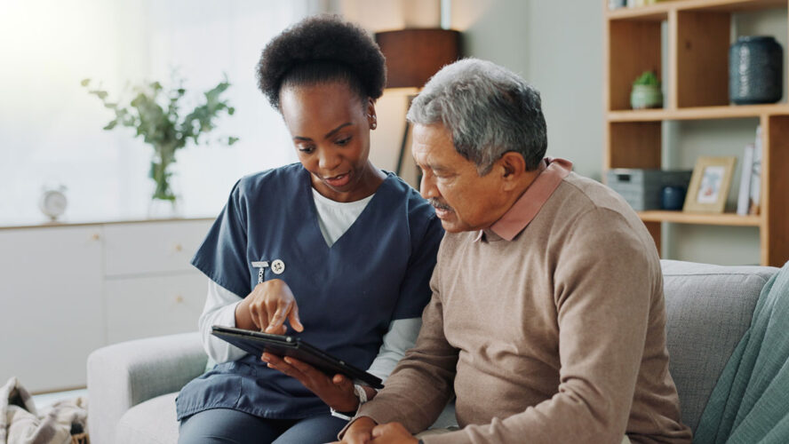 Nurse, senior and discussion with tablet on sofa for healthcare, communication or consultation at home. Woman or medical caregiver helping and talking to elderly male person on technology for advice