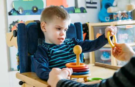 Activities for kids with disabilities. Preschool Activities for Children with Special Needs. Boy with with Cerebral Palsy in special chair play with mom at home