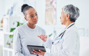 Doctor, woman and tablet for hospital, healthcare advice and support for results, exam and test on bed. Senior expert or medical people on digital tech for clinic sign up, registration and consulting