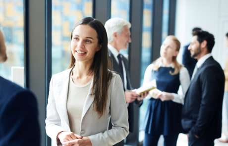 Smiling pretty young business lady in jacket talking to colleague and discussing business forum topics during break