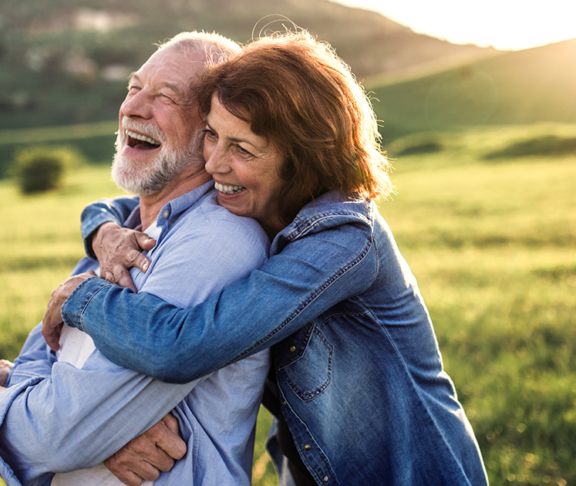 Side view of senior couple hugging outside in spring nature at sunset