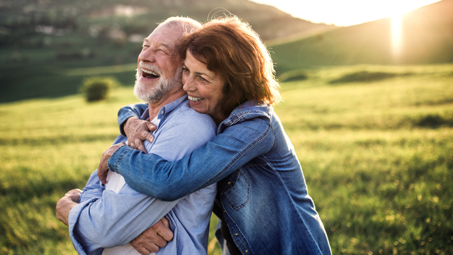 Side view of senior couple hugging outside in spring nature at sunset
