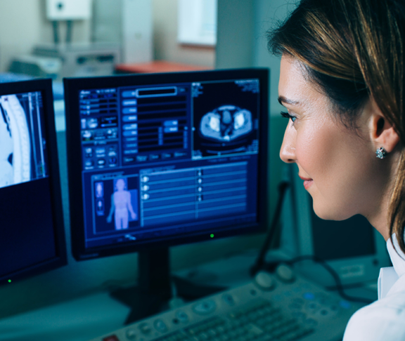 Radiologist reading a CT scan. Female doctor running CT scan from control room at hospital