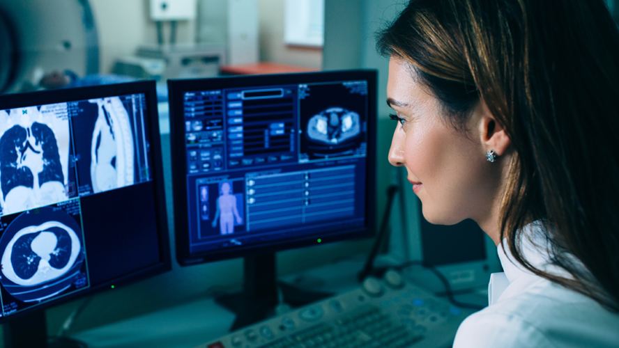 Radiologist reading a CT scan. Female doctor running CT scan from control room at hospital