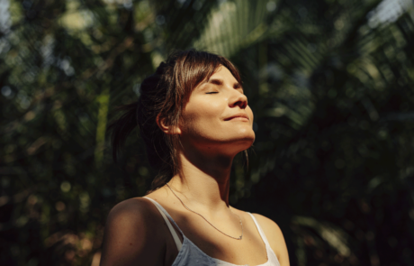 Beautiful Happy Woman Enjoying the Warm Sunlight in a Tropical Public Park