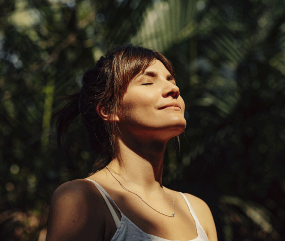 Beautiful Happy Woman Enjoying the Warm Sunlight in a Tropical Public Park