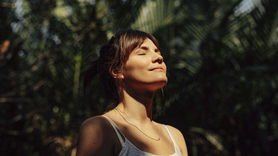 Beautiful Happy Woman Enjoying the Warm Sunlight in a Tropical Public Park