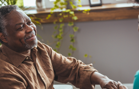 Female carer holding hands of senior man