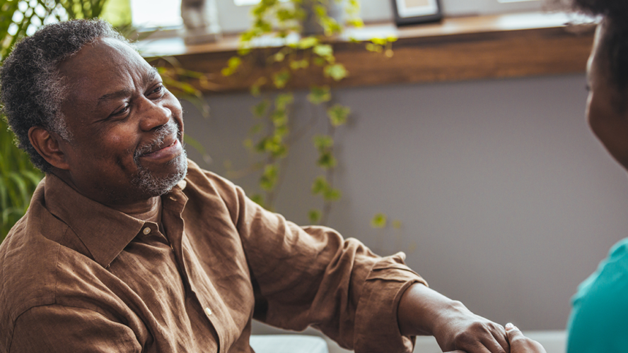 Female carer holding hands of senior man