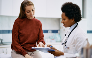 Happy woman going through her medical data with black female doctor at the clinic